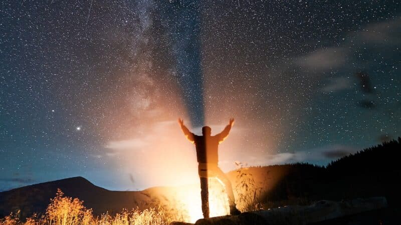 Male traveler standing under beautiful night sky with stars. Selbstfindung - manche gehen auf Wanderschaft, um sich selbst zu finden.