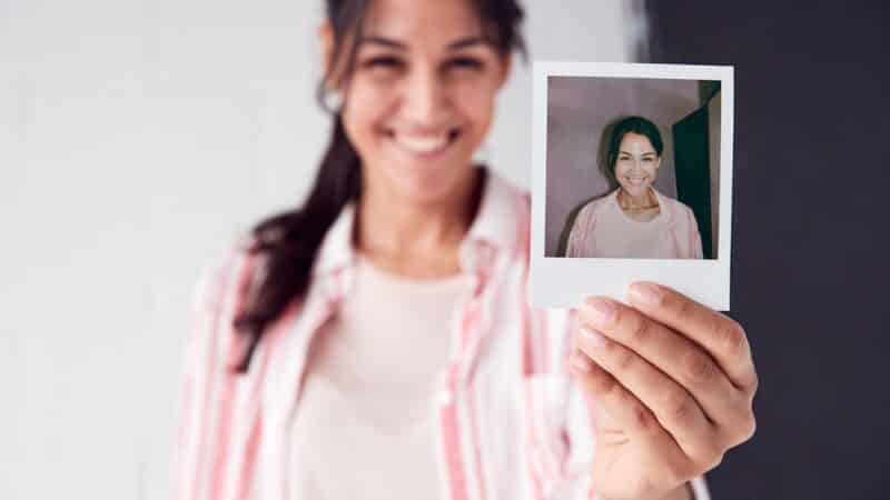 Portrait Of Female Photographer On Photo Shoot Holding Up Instant Polaroid Print In Studio Selbstfindung -beschäftige Dich mit Deinem Inneren