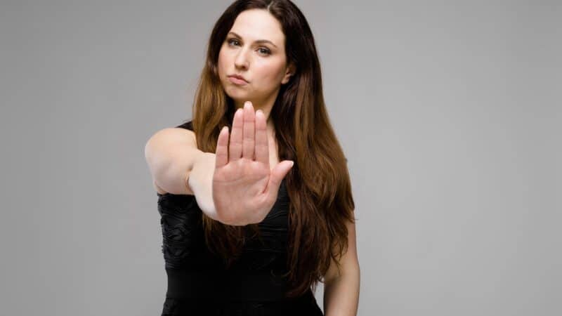 Emotional pretty confident serious plus size model standing in studio showing stop sign on gray background Manchmal braucht es Zivilcourage und Durchsetzungsvermögen, um seine Ziele zu verfolgen.